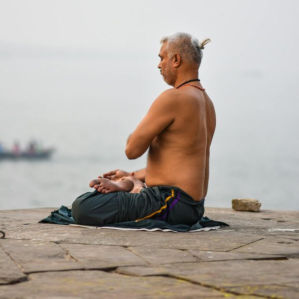 A serene man meditating outdoors at sunrise, symbolizing peace and well-being.