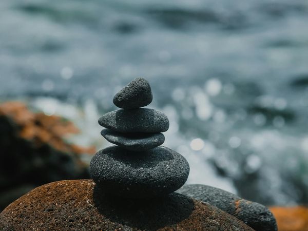Stones stacked in a perfect balance on a beach, representing the philosophy of balance and stability.